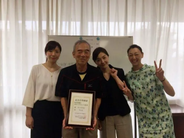 表彰状を手に記念撮影する4人