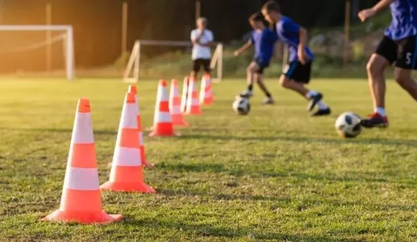 サッカーの練習でコーンドリブルをする少年たち