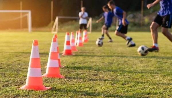 サッカーの練習でコーンドリブルをする少年たち