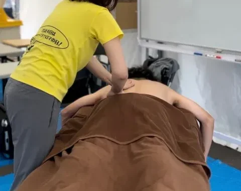 テント内で選手の背中をケアするスポーツアロマトレーナー