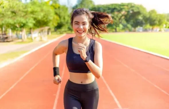 陸上トラックを笑顔で走る女性ランナー