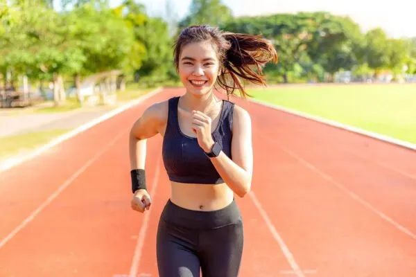 陸上トラックを笑顔で走る女性ランナー
