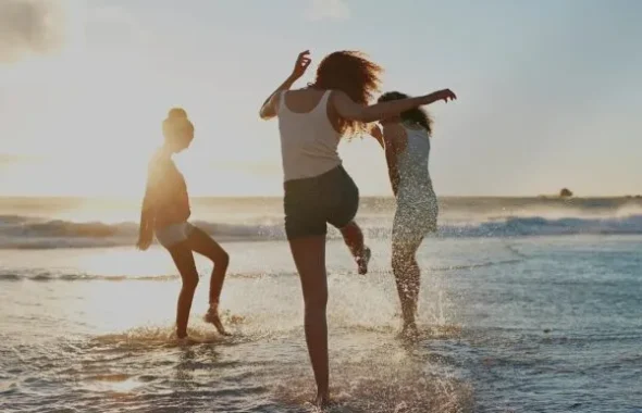 夕暮れの海辺で楽しそうに走る3人の女性たち