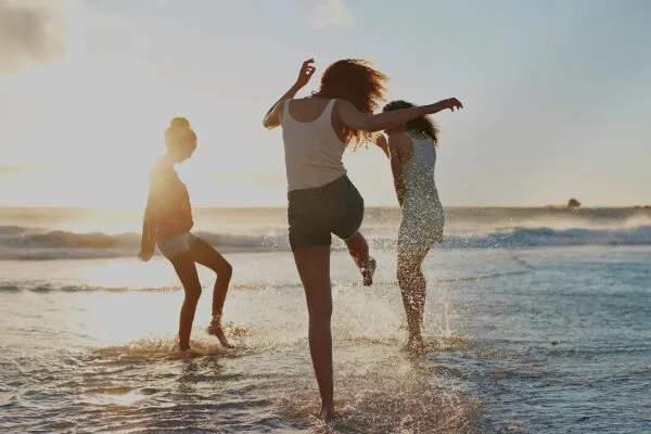 夕暮れの海辺で楽しそうに走る3人の女性たち