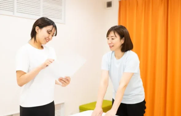 施術ルームで資料を見ながら会話する女性2人