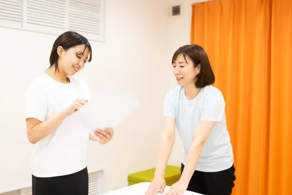 施術ルームで資料を見ながら会話する女性2人