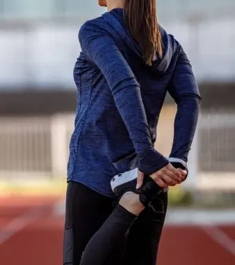 陸上トラックでストレッチをする女性の後ろ姿