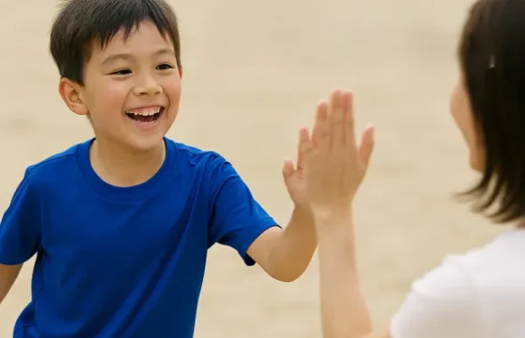 砂浜でハイタッチをする男の子と母親