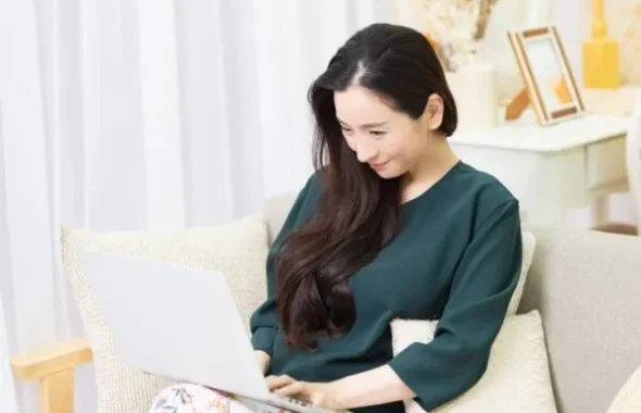 ソファでノートパソコンを操作する女性