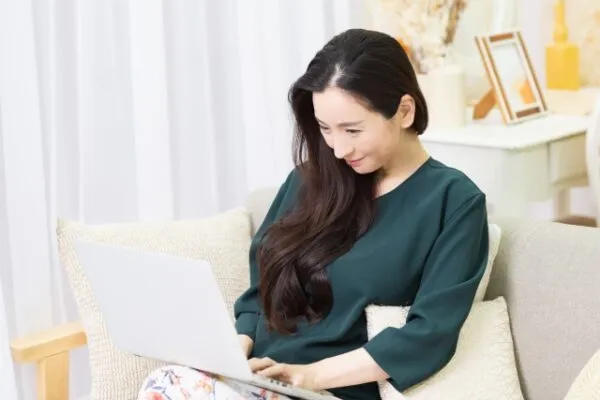 ソファでノートパソコンを操作する女性