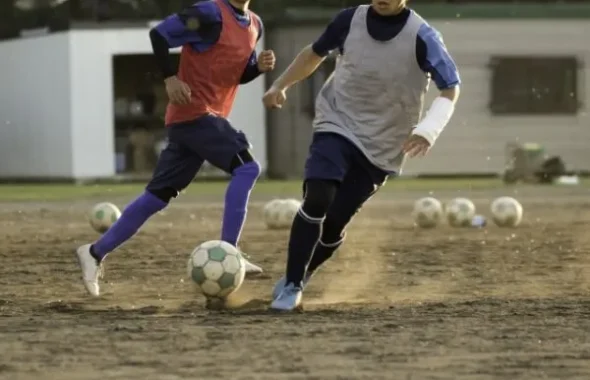 サッカーの練習で走る中学生の選手2人