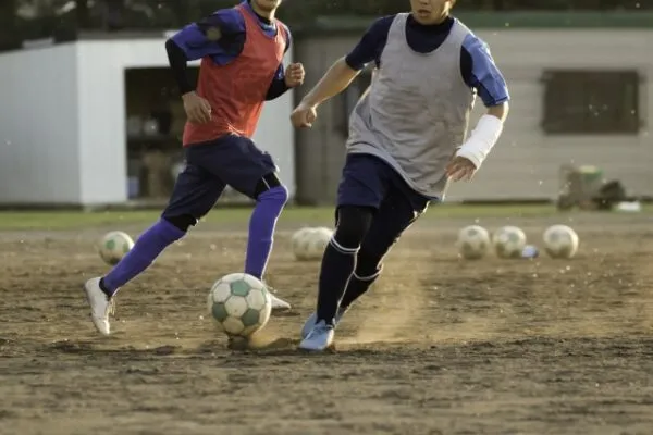 サッカーの練習で走る中学生の選手2人