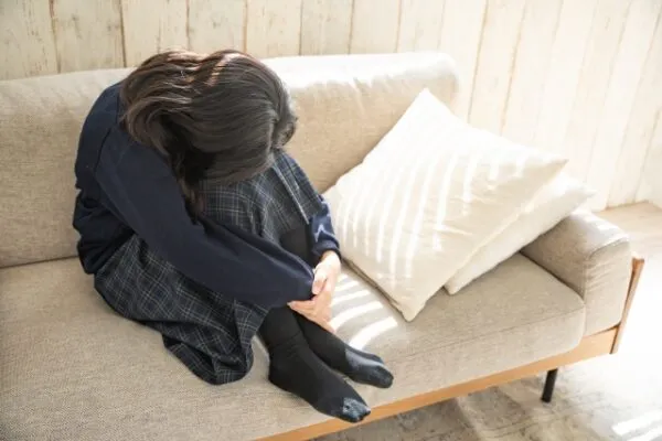 ソファでうずくまり体調不良の様子の女子学生