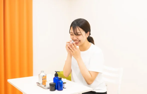 精油の香りを嗅いで笑顔の女性とアロマ用品