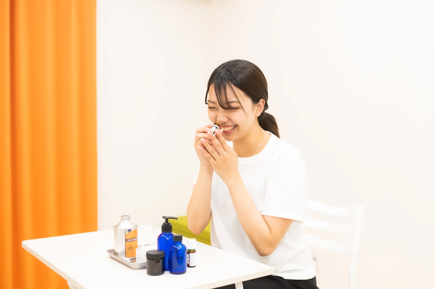 精油の香りを嗅いで笑顔の女性とアロマ用品