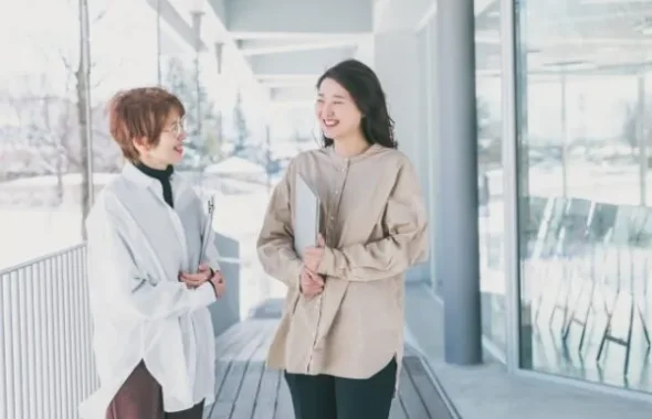 資料を持って会話する女性2人