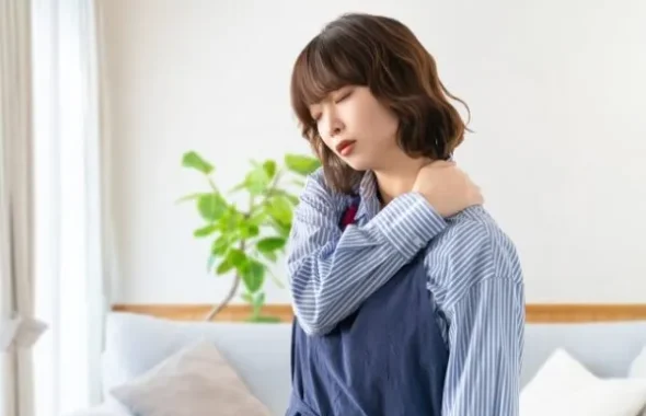 肩に手を当てて疲れた様子の女性