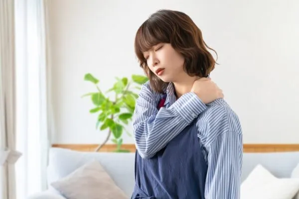 肩に手を当てて疲れた様子の女性
