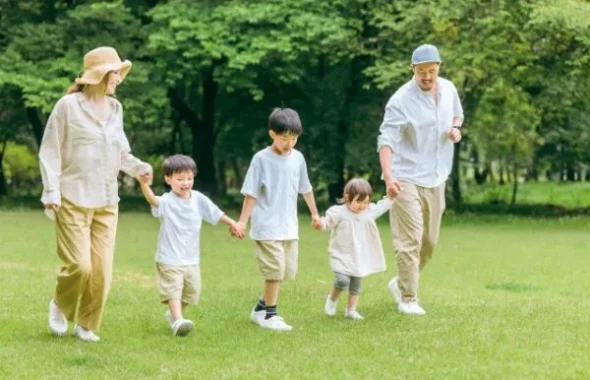 公園で手をつないで歩く家族と子供たち