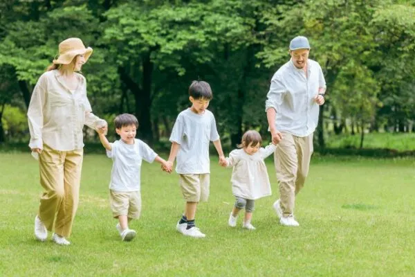 公園で手をつないで歩く家族と子供たち