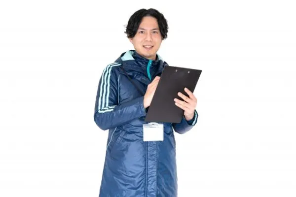 クリップボードを持つ指導者風の男性