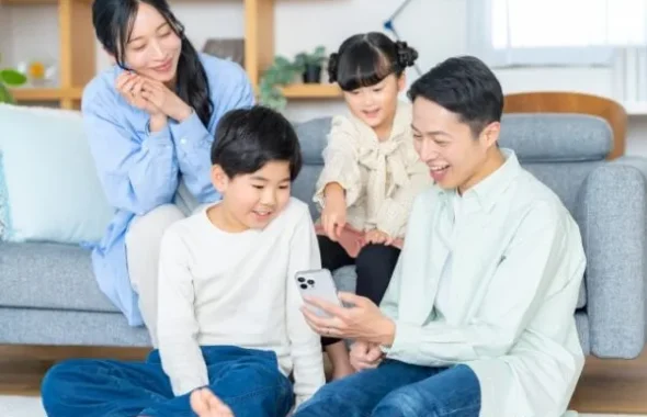 リビングでスマートフォンを見る家族4人