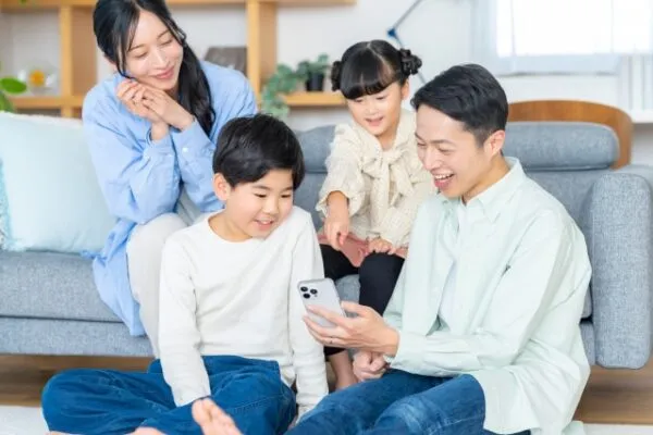 リビングでスマートフォンを見る家族4人