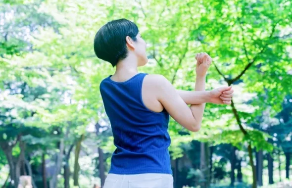公園で腕をストレッチする女性の後ろ姿