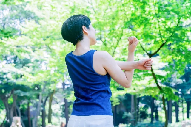 公園で腕をストレッチする女性の後ろ姿