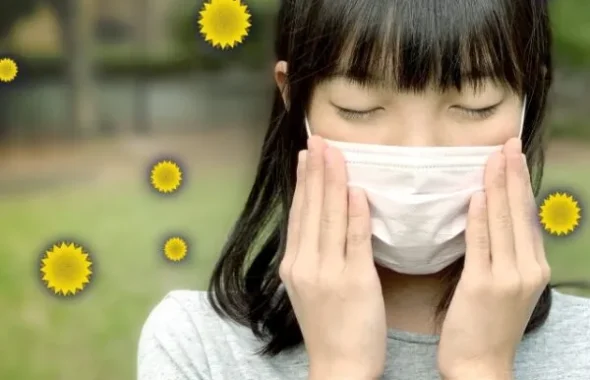 マスクをして目を閉じる花粉症の女の子