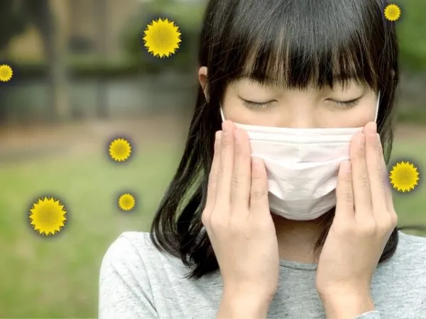 マスクをして目を閉じる花粉症の女の子