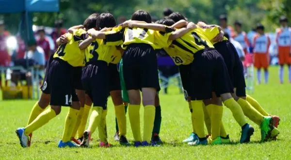円陣を組むサッカーユニフォーム姿の少年たち