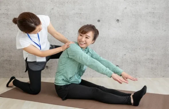 ストレッチを補助するトレーナーと女性