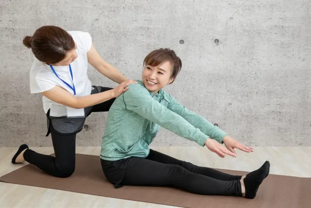 ストレッチを補助するトレーナーと女性