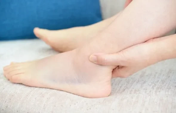 足首を手で押さえる人の脚