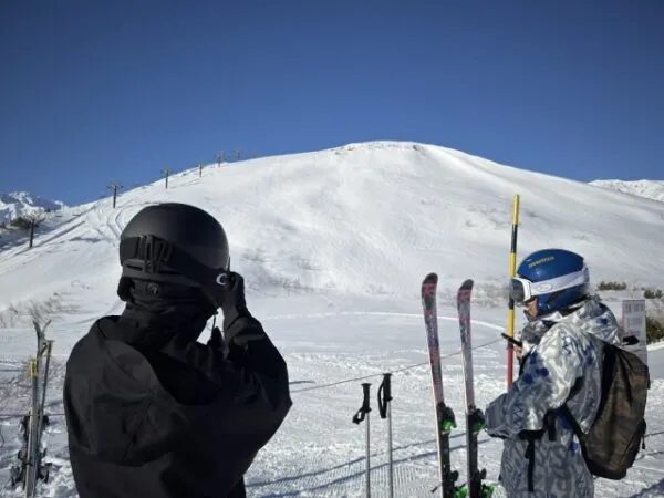 雪山でスキー用具を持つ2人の後ろ姿