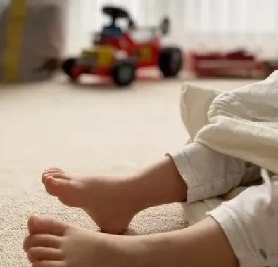 おもちゃが並ぶ部屋で座る子供の足元