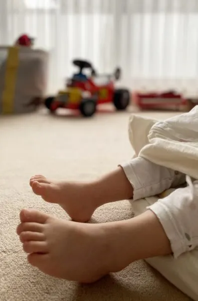 おもちゃが並ぶ部屋で座る子供の足元
